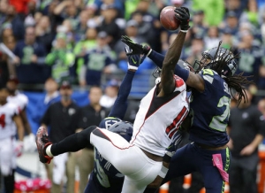 Seattle Seahawks cornerback Richard Sherman, right, and Earl Thomas (obscured) break up a pass intended for Atlanta Falcons wide receiver Julio Jones (11) in the second half of an NFL football game, Sunday, Oct. 16, 2016, in Seattle. The Seahawks beat the Falcons 26-24. (AP Photo/Elaine Thompson)