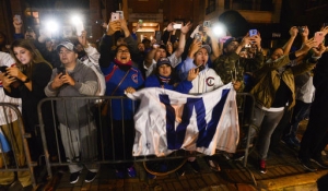 Fans celebrate outside Wrigley Field as buses carrying the Chicago Cubs baseball team arrive in Chicago early Thursday, Nov. 3, 2016, after the Cubs defeated the Cleveland Indians 8-7 in Game 7 of the World Series in Cleveland. (AP Photo/Matt Marton)